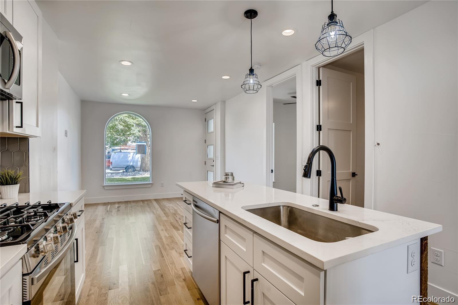443 Inca Street Denver, CO 80204 - Photo 4 of 13 a kitchen that has a sink a stove and a wooden floor
