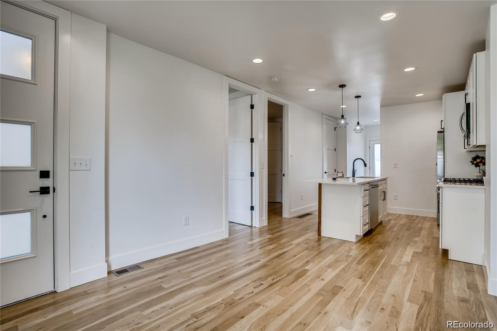 443 Inca Street Denver, CO 80204 - Photo 5 of 13 a view of kitchen with stainless steel appliances refrigerator oven and white cabinets with wooden floor