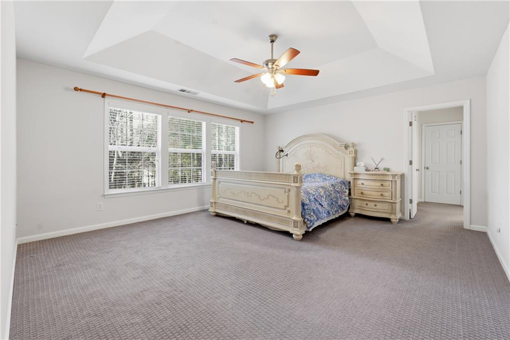 38 Crystal Downs Way Northeast Suwanee, GA 30024 - Photo 24 of 44 a spacious bedroom with a bed a chandelier and large window