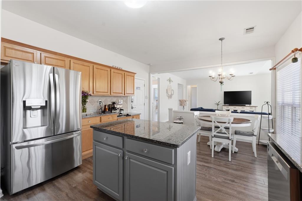38 Crystal Downs Way Northeast Suwanee, GA 30024 - Photo 9 of 44 a kitchen with stainless steel appliances granite countertop a refrigerator a stove a sink a dining table and chairs with wooden floor