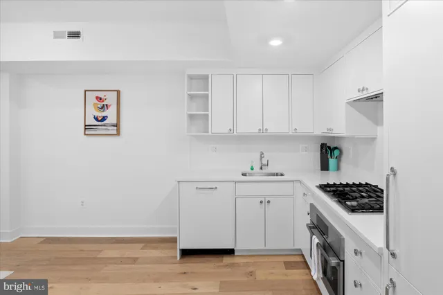 a kitchen with stainless steel appliances a stove a white cabinet and a granite counter tops