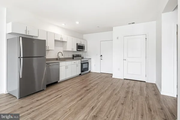 a kitchen with a refrigerator a stove top oven and wooden floor