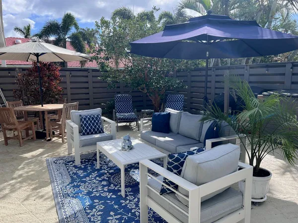 a view of a patio with couches table and chairs under an umbrella