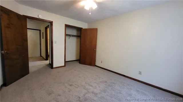 an empty room with closet and a chandelier fan