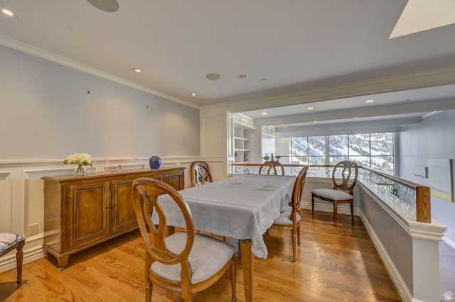 9699 Bypass Road, Unit 5 Alta, UT 84092 - Photo 18 of 54 Formal dining area featuring hardwood flooring, wainscoting, recessed lighting, and a glass-paneled railing overlooking an expansive window with a mountain backdrop