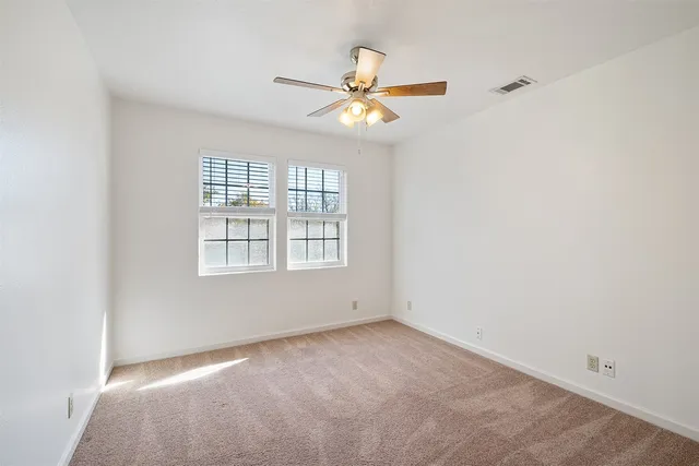 an empty room with a window and a fan