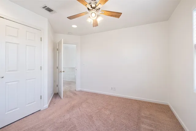 an empty room with closet and a chandelier fan