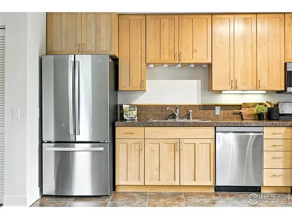 a kitchen with granite countertop a refrigerator a sink and white cabinets
