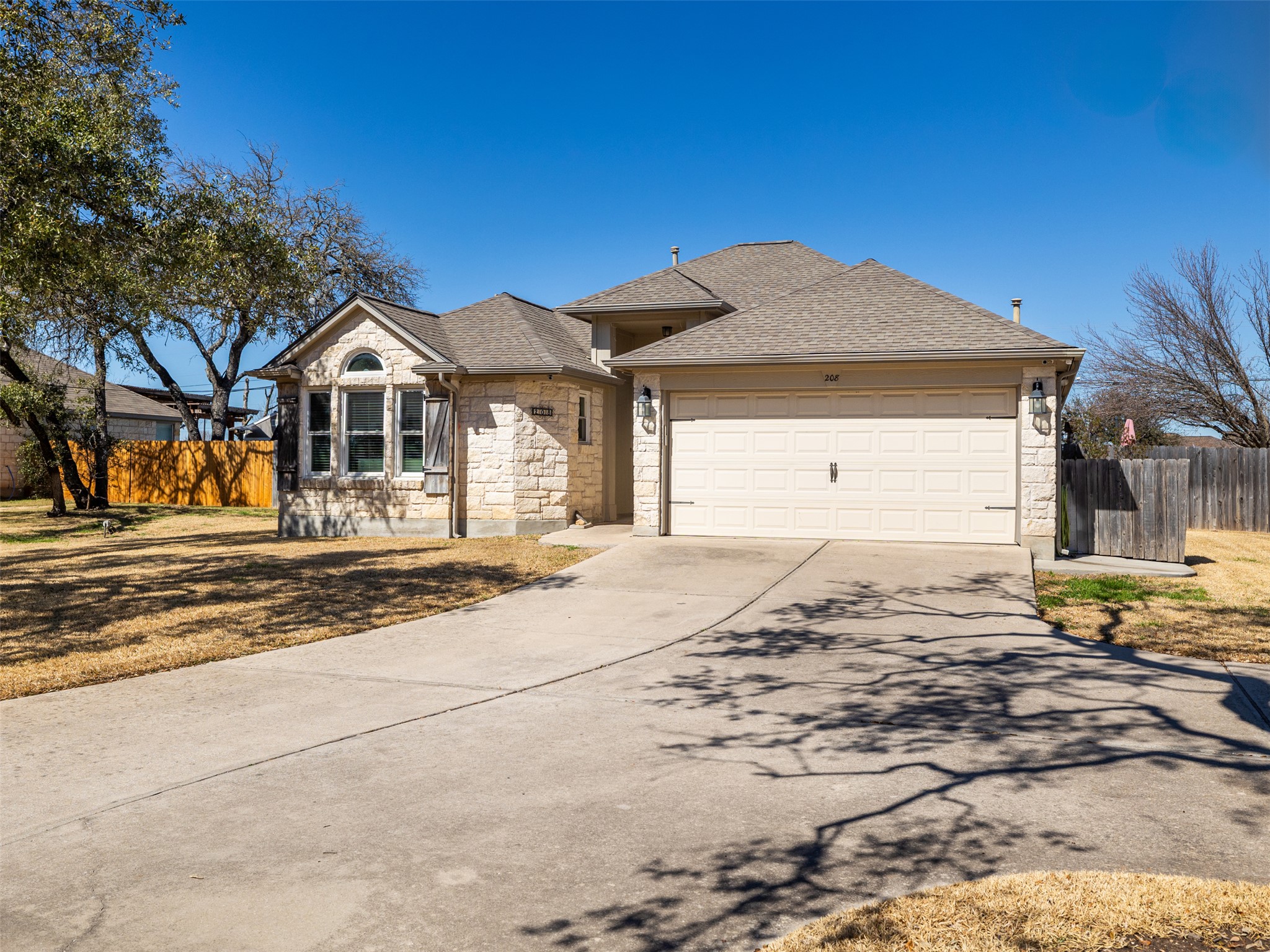 208 South Buffalo Pass Georgetown, TX 78633 - Photo 4 of 28 Ranch-style house featuring stone siding, concrete driveway, an attached garage, and a shingled roof