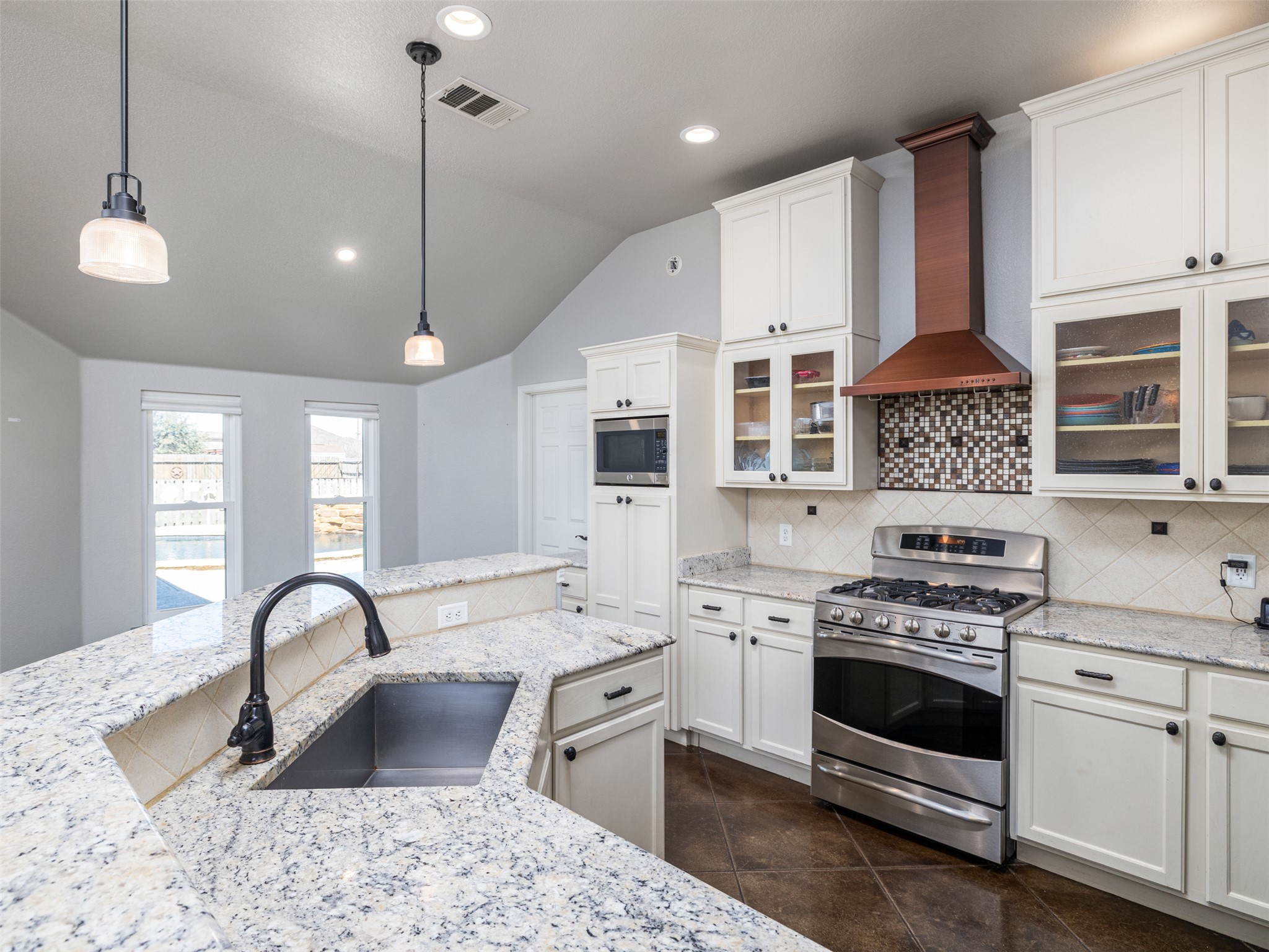 208 South Buffalo Pass Georgetown, TX 78633 - Photo 8 of 28 Kitchen featuring stainless steel appliances, vaulted ceiling, pendant lighting, backsplash, and white cabinets