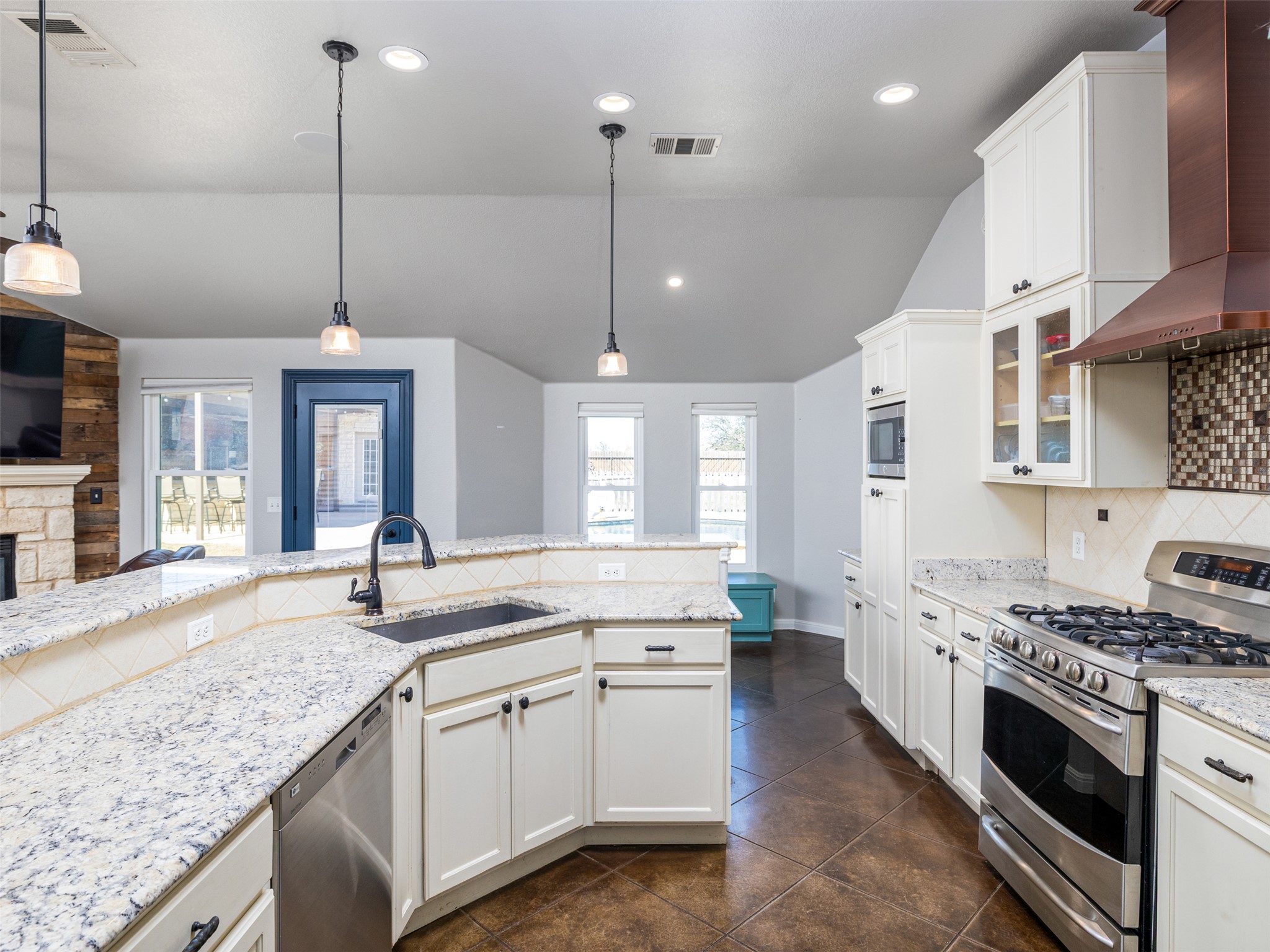 208 South Buffalo Pass Georgetown, TX 78633 - Photo 9 of 28 Kitchen with backsplash, vaulted ceiling, stainless steel appliances, light stone counters, and white cabinets