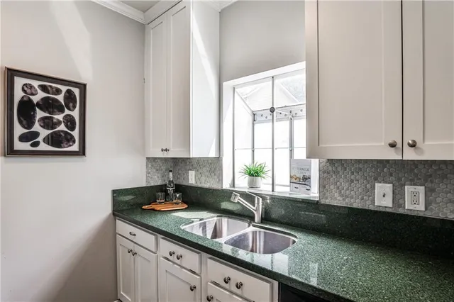 a kitchen with granite countertop a sink a window and cabinets