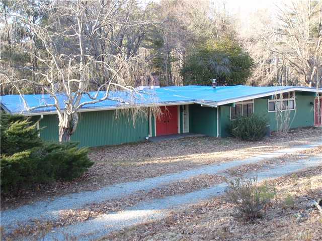 a view of a barn with large trees plants and large trees
