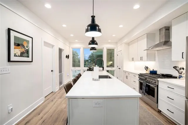 a kitchen that has a lot of white cabinets and a wooden floor