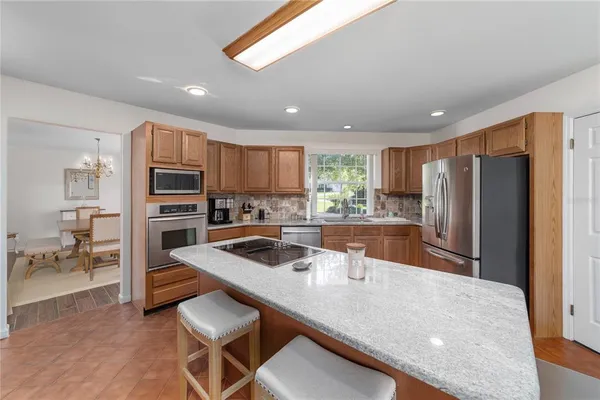 a kitchen with stainless steel appliances granite countertop a refrigerator a sink and a stove