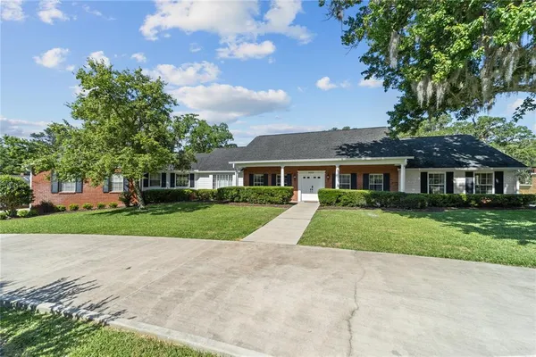 a view of a brick house next to a yard with big trees