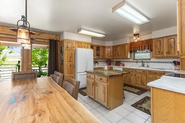 a kitchen with stainless steel appliances granite countertop a refrigerator a sink dishwasher a stove and white cabinets with wooden floor