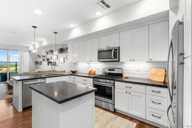 a kitchen with kitchen island granite countertop a sink a stove cabinets and wooden floor