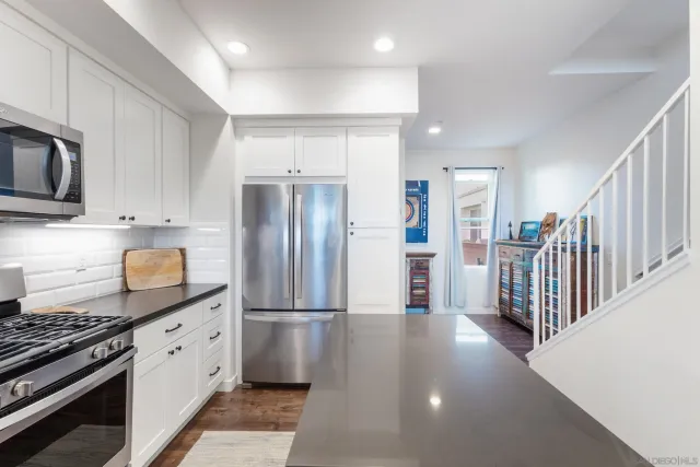 a kitchen with stainless steel appliances granite countertop a refrigerator and a stove top oven