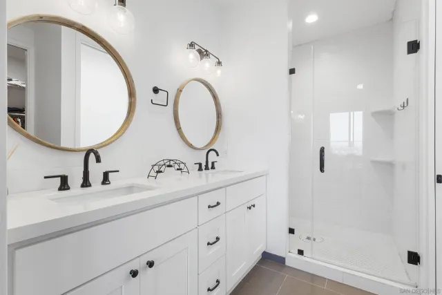 a bathroom with a double vanity sink mirror and shower