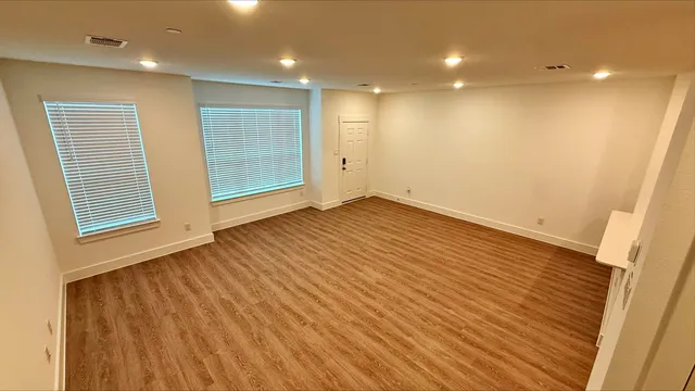 an empty room with wooden floor and windows