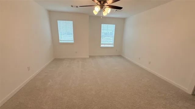 an empty room with windows and fan