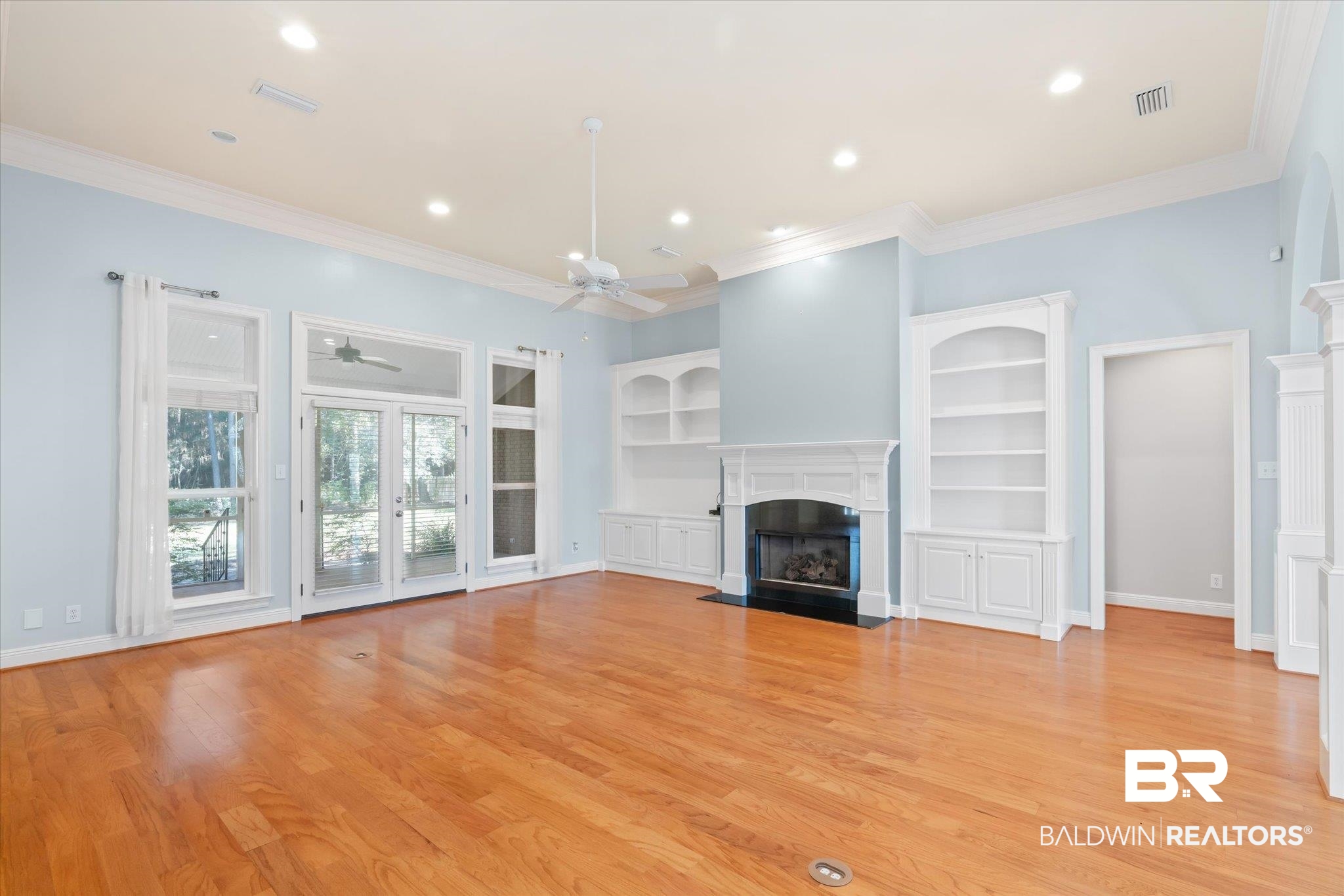 10730 Flagstone Drive Mobile, AL 36608 - Photo 4 of 20 Unfurnished living room featuring ceiling fan, crown molding, light wood-type flooring, and built in shelves