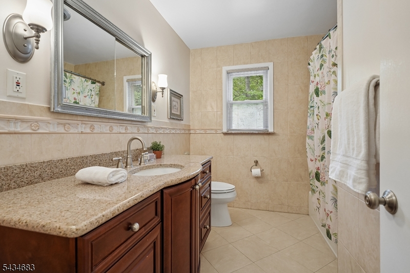 106 Division Avenue Summit, NJ 07901 - Photo 22 of 38 a bathroom with a granite countertop sink and a mirror