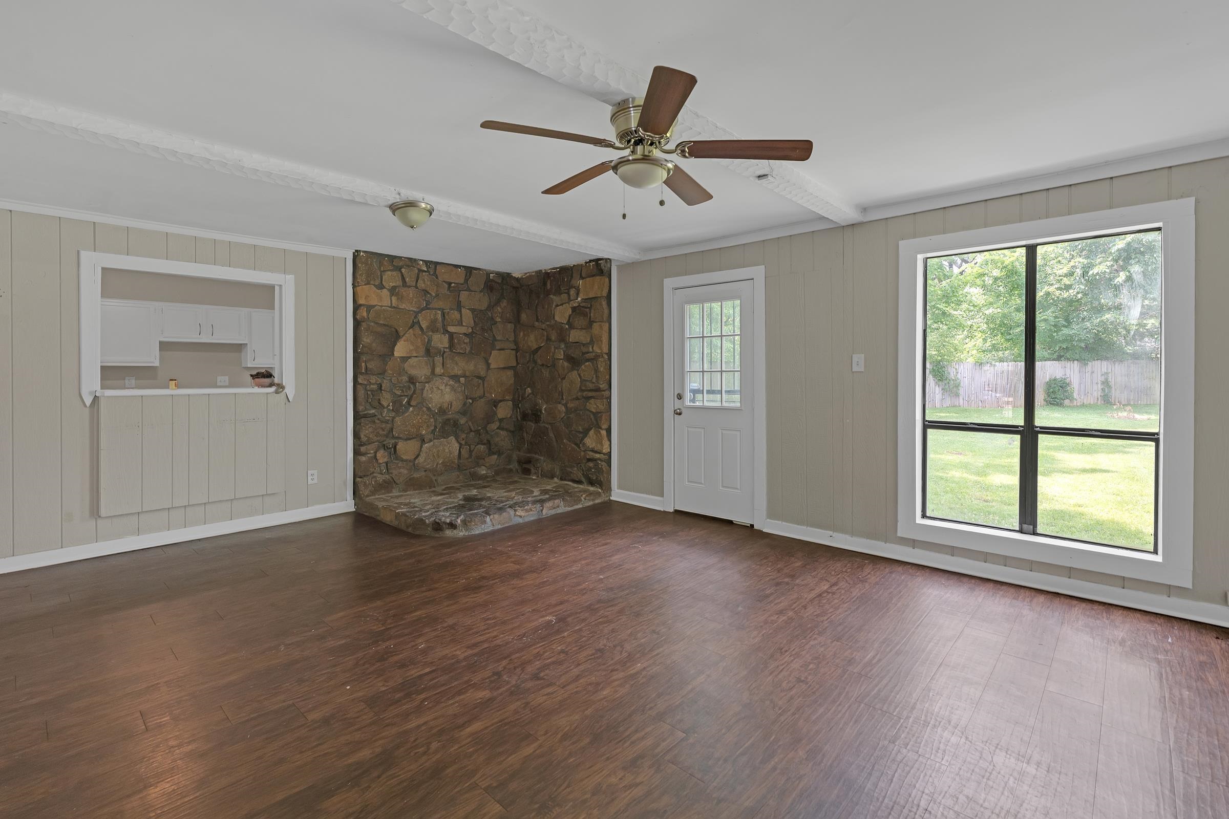6128 Raintree Drive Memphis, TN 38115 - Photo 13 of 30 Unfurnished living room featuring beamed ceiling, wood walls, dark wood-type flooring, and ceiling fan