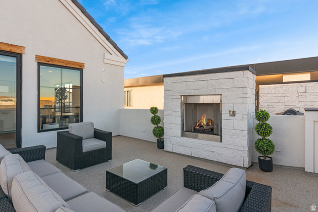 5367 Cyan Lane St. George, UT 84790 - Photo 40 of 49 Rooftop patio featuring a stacked stone fireplace with stainless steel insert, light-toned textured stucco walls, and large black-framed windows with wood lintels