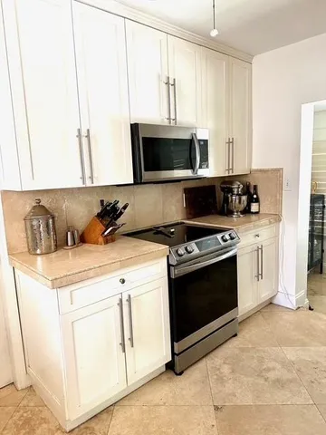 a kitchen with white cabinets and appliances