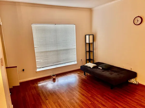 a view of an empty room with wooden floor and a ceiling fan