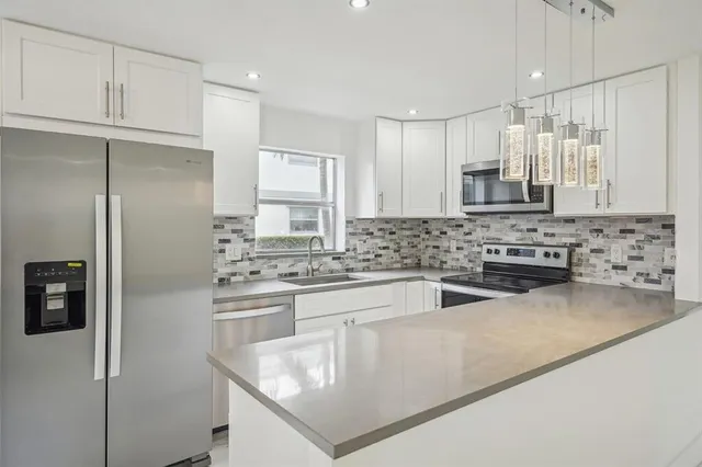 a kitchen with stainless steel appliances granite countertop a sink a stove a refrigerator a microwave and island