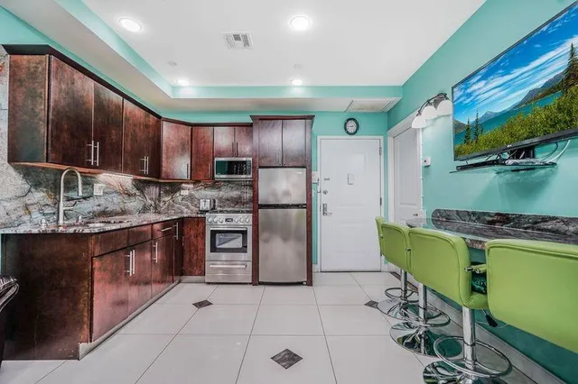 a kitchen with stainless steel appliances kitchen island granite countertop a refrigerator and a sink