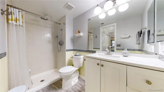 a bathroom with a sink vanity granite toilet and shower