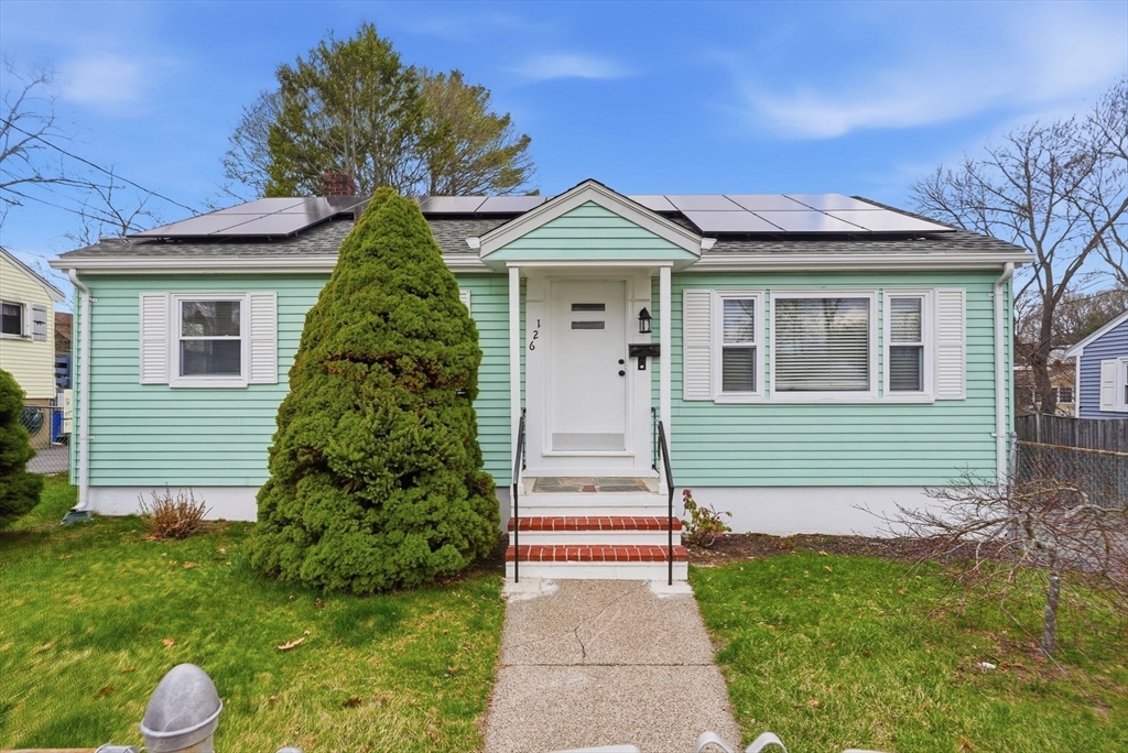 a front view of a house with a yard and potted plants