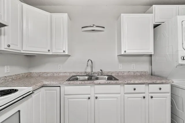 a kitchen with granite countertop white cabinets and a sink