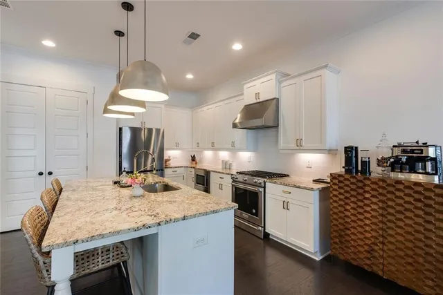a kitchen with kitchen island granite countertop a sink a counter space appliances and cabinets