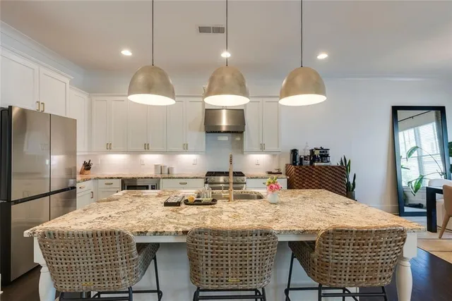 a kitchen with granite countertop a table chairs stainless steel appliances and wooden floor