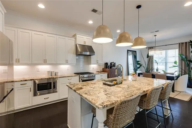 a kitchen with stainless steel appliances granite countertop a stove a sink a microwave a dining table and chairs