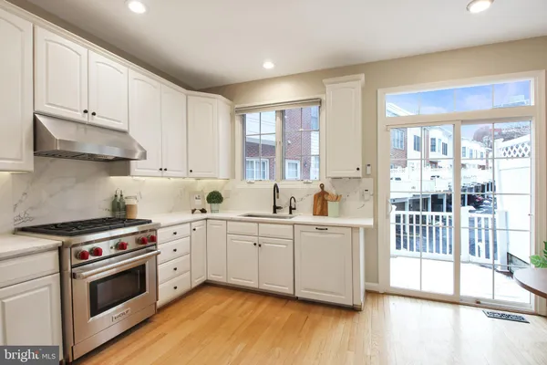 a kitchen with stainless steel appliances granite countertop a stove a sink and white cabinets