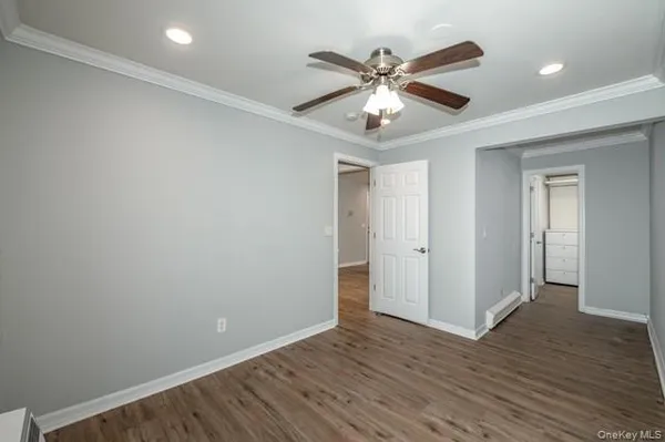 a view of an empty room with wooden floor and a ceiling fan