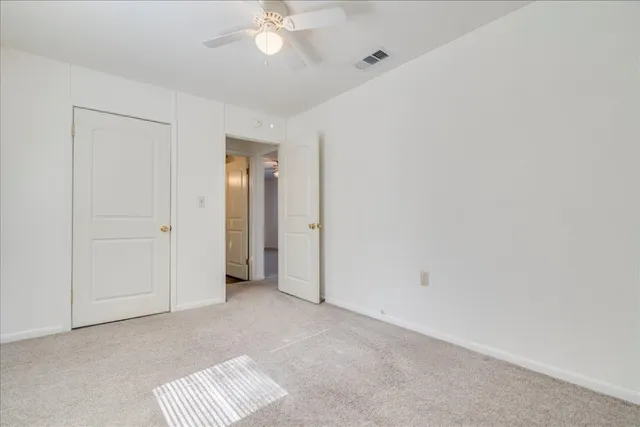 an empty room with a chandelier fan and closet