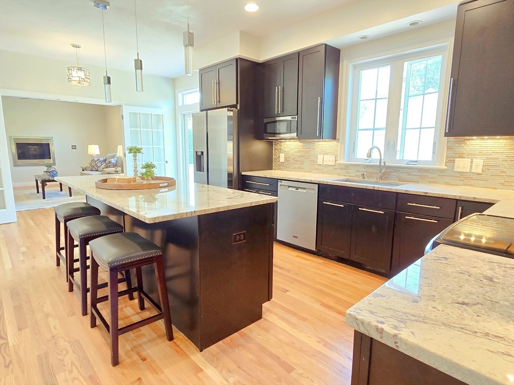 3 Willow Road Ashland, MA 01721 - Photo 15 of 41 a large kitchen with stainless steel appliances kitchen island granite countertop a table chairs sink and cabinets