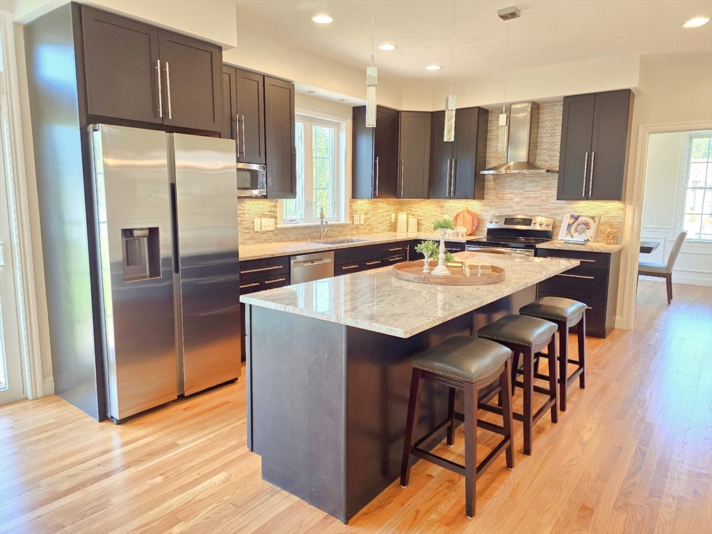 3 Willow Road Ashland, MA 01721 - Photo 17 of 41 a kitchen with granite countertop a refrigerator a stove a sink a dining table and chairs