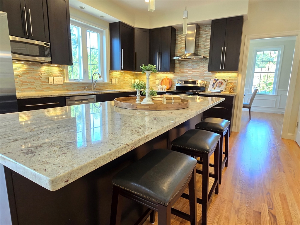 3 Willow Road Ashland, MA 01721 - Photo 21 of 41 a kitchen with stainless steel appliances kitchen island granite countertop a table chairs in it and wooden floors