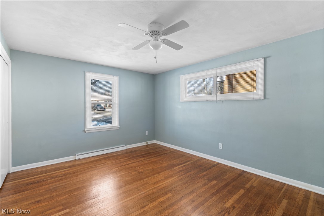 136 South Metzger Avenue Rittman, OH 44270 - Photo 8 of 33 Unfurnished room featuring baseboard heating, wood-type flooring, and a ceiling fan