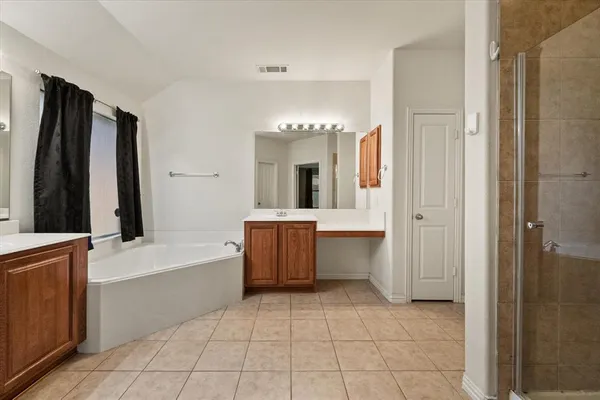 a large spacious bathroom with a tub a sink and a mirror