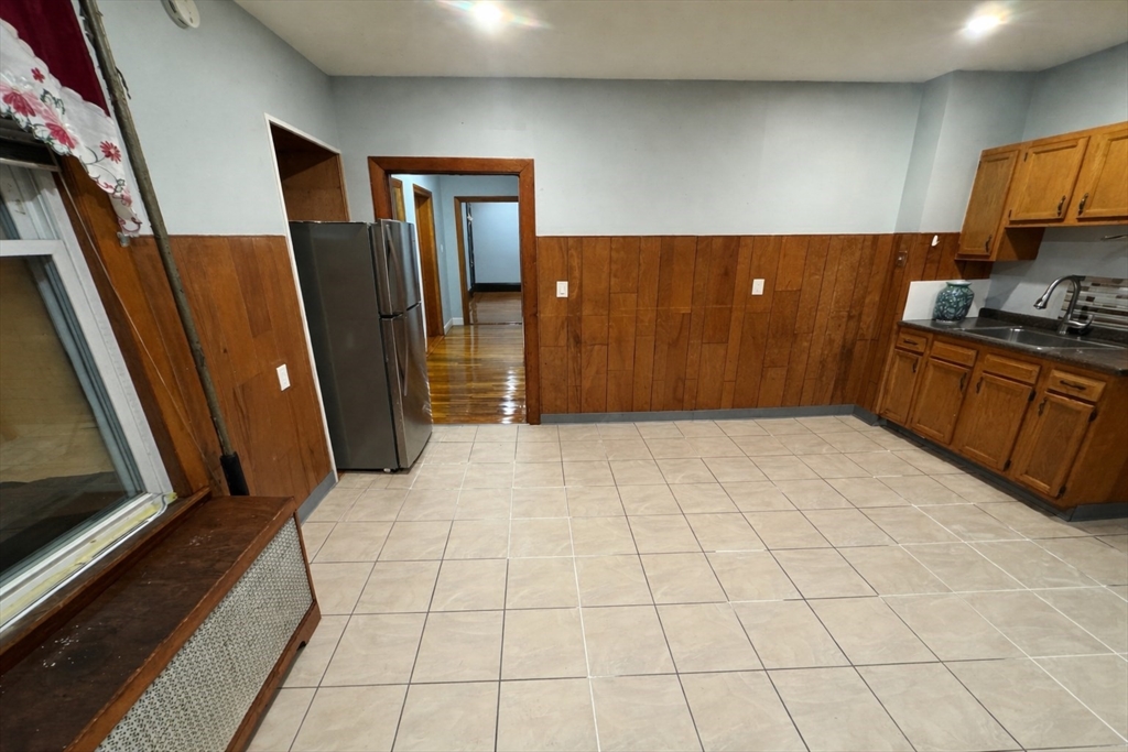 140 Butler Street, Unit 1 Revere, MA 02151 - Photo 4 of 5 a view of a refrigerator in kitchen and an empty room in wooden floor