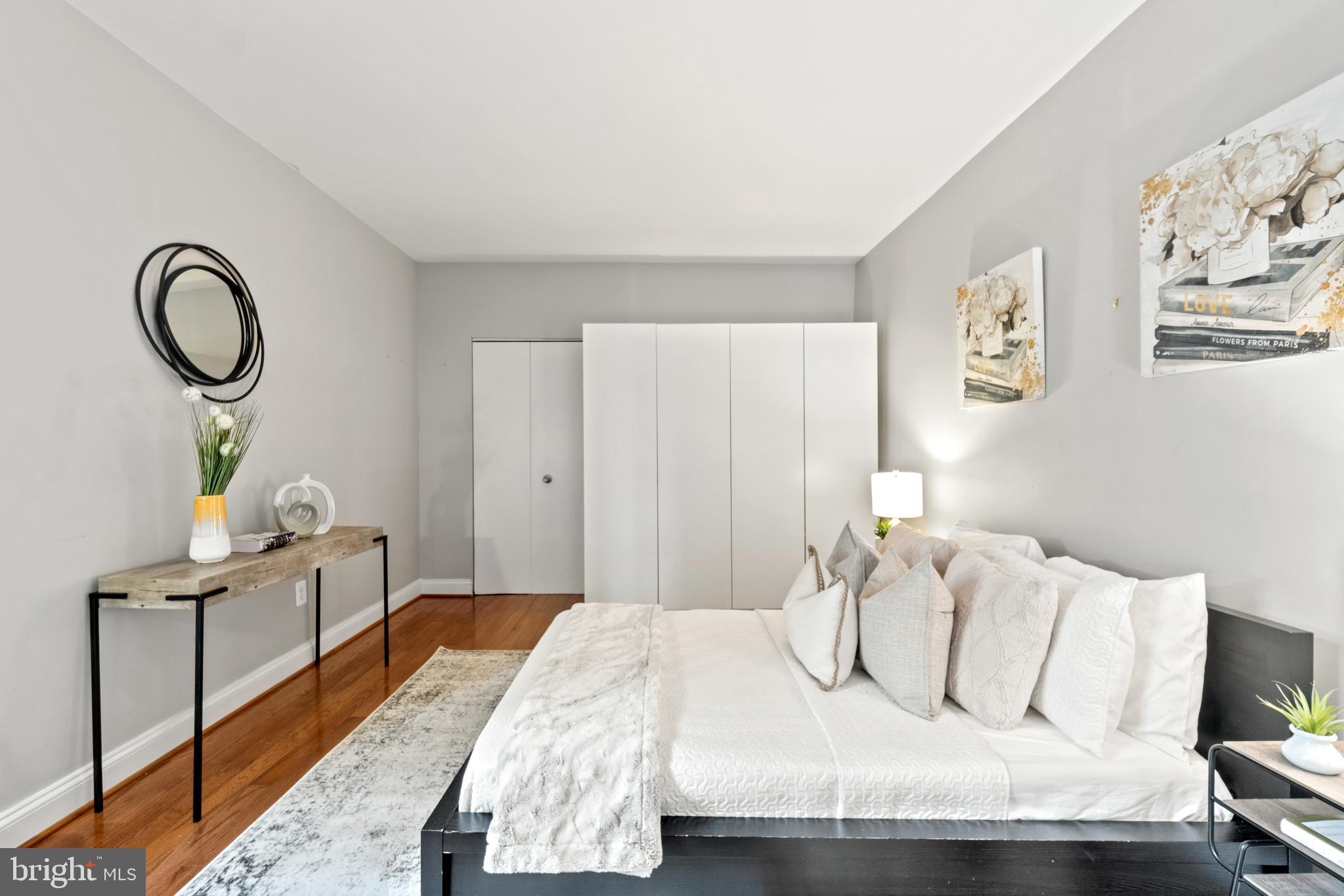 1701 16th Street Northwest, Unit 421 Washington, DC 20009 - Photo 13 of 20 a bedroom with a bed and a dresser with wooden floor